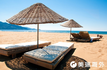 Sunbeds and rattan parasols on sandy seaside.jpg